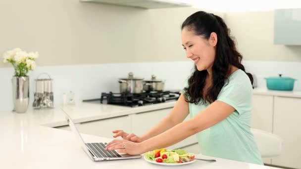 Csinos nő használ laptop, és eszik saláta — Stock videók