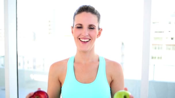 Sonriente mujer en forma mostrando dos manzanas — Vídeos de Stock