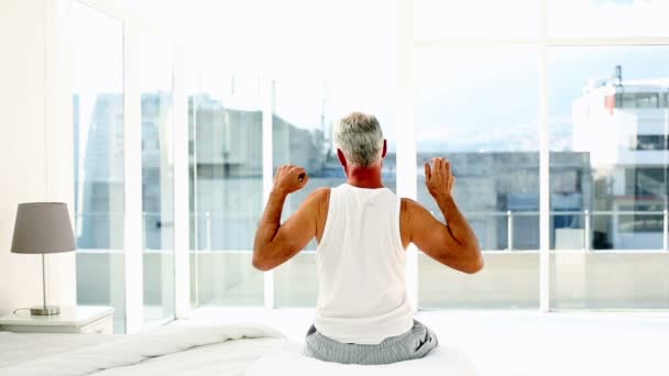 Mature man yawning and stretching sitting on bed — Stock Video