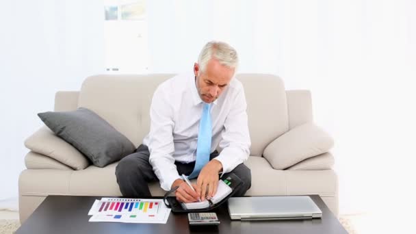 Empresario escribiendo en su diario y sonriendo a la cámara — Vídeos de Stock