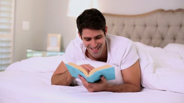 Gelukkig knappe man lezen in bed — Stockvideo