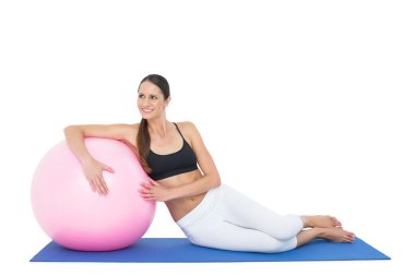 gülümseyen fit fitness topu ile oturan genç kadın