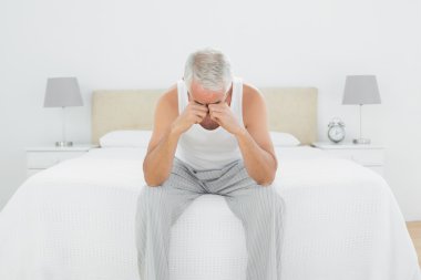 düşünceli olgun adam yatakta oturuyor