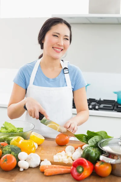 Lächelnde Frau, die in der Küche Gemüse hackt — Stockfoto