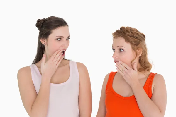 Dos amigas jóvenes sorprendidas con la mano sobre la boca — Foto de Stock