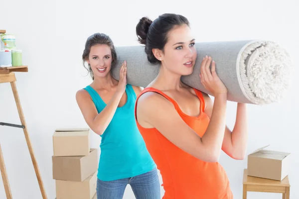 Vrienden uitvoering tapijt gerold na zijn verhuizing in een huis — Stockfoto