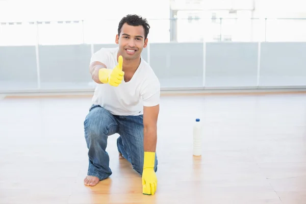 Uomo pulizia del pavimento mentre gesticolando pollici a casa — Foto Stock