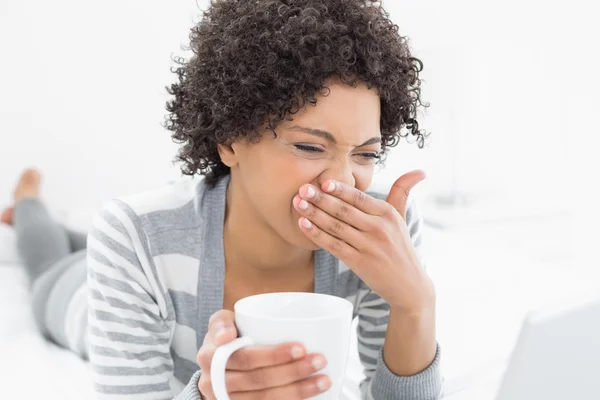 Vrouw met koffie beker met behulp van laptop in bed — Stockfoto