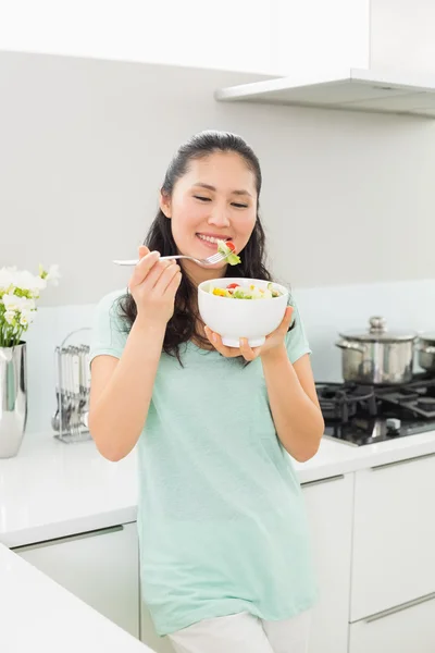 Gülümseyen genç kadın mutfakta salata bir kase ile — Stok fotoğraf