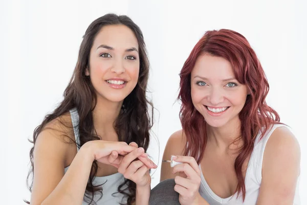 Sonriendo bonita joven mujer pintando las uñas de un amigo —  Fotos de Stock