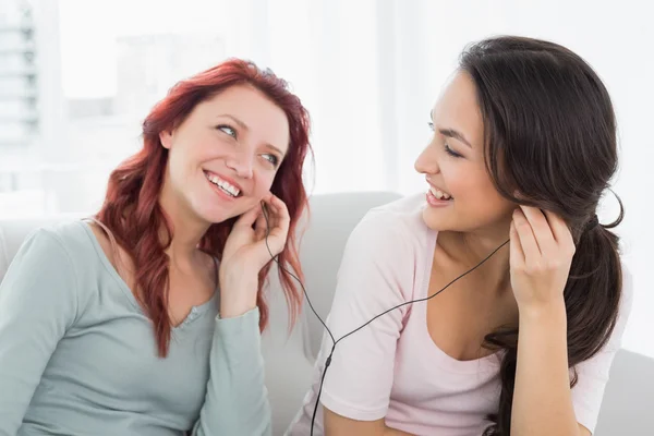 Vrienden luisteren muziek via oortelefoons samen thuis — Stockfoto