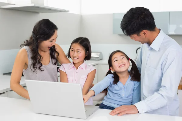 Glückliche vierköpfige Familie nutzt Laptop in Küche — Stockfoto