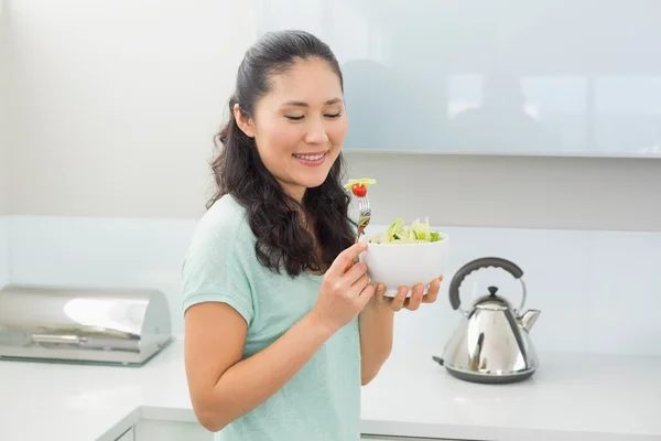 Mujer sonriente con un tazón de ensalada en la cocina — Foto de Stock