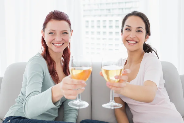 Happy female friends holding out wine glasses at home — Stock Photo, Image