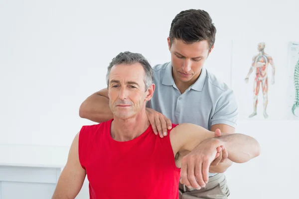 Fisioterapeuta masculino estirando un brazo de hombre maduro —  Fotos de Stock