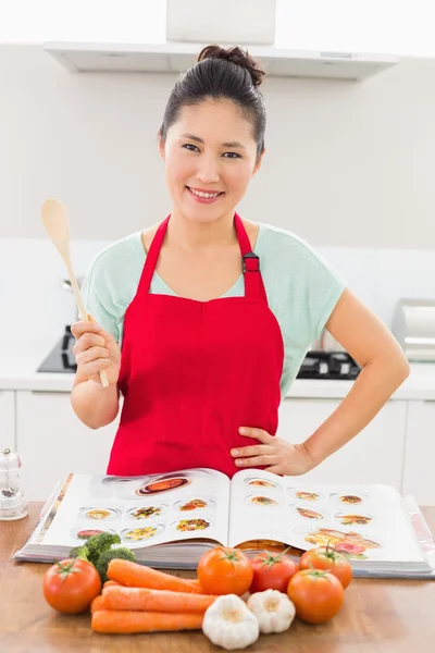 Mujer sonriente con libro de recetas y verduras en la cocina —  Fotos de Stock