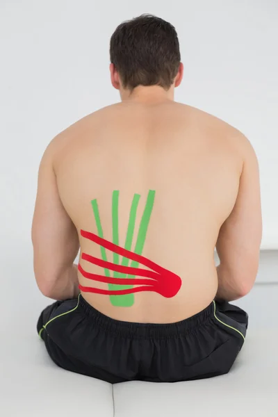 Shirtless man with red and green kinesio tapes on back — Stock Photo, Image