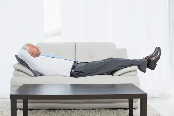 Tired mature businessman sleeping on sofa in living room — Stock Photo, Image