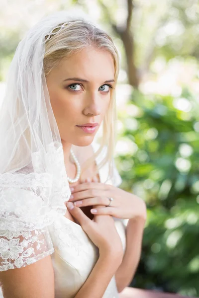 Sposa bionda con un velo che le tiene le mani al petto — Foto Stock