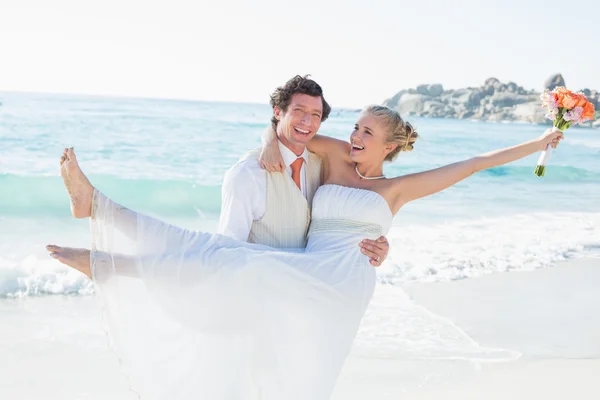 Laughing groom carrying his pretty blonde wife — Stock Photo, Image