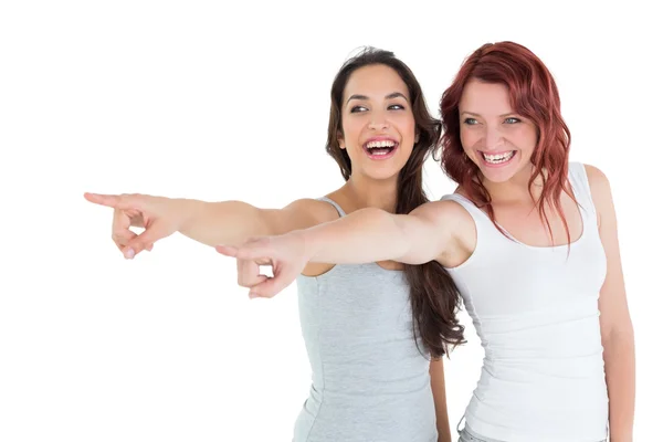 Two cheerful female friends pointing away — Stock Photo, Image