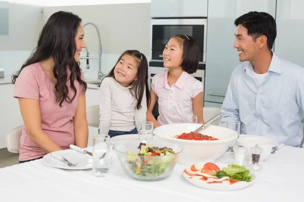 Famille souriante de quatre personnes assises à table dans la cuisine — Photo