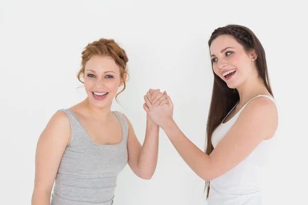 Portrait of two casual young female friends arm wrestling — Stock Photo, Image