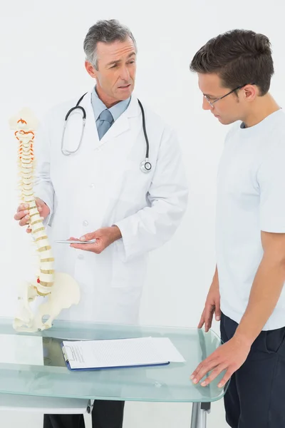 Médico explicando a coluna vertebral ao paciente no consultório — Fotografia de Stock