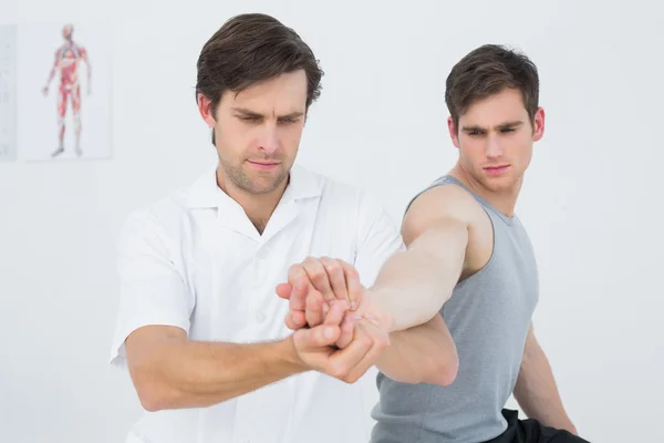 Manlig sjukgymnast undersöka en ung mans hand — Stockfoto