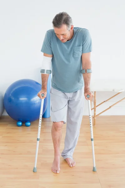 Mature man with crutches at gym hospital — Stock Photo, Image