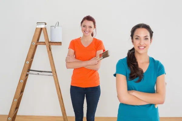 Vrienden met verf penselen en ladder in een nieuw huis — Stockfoto