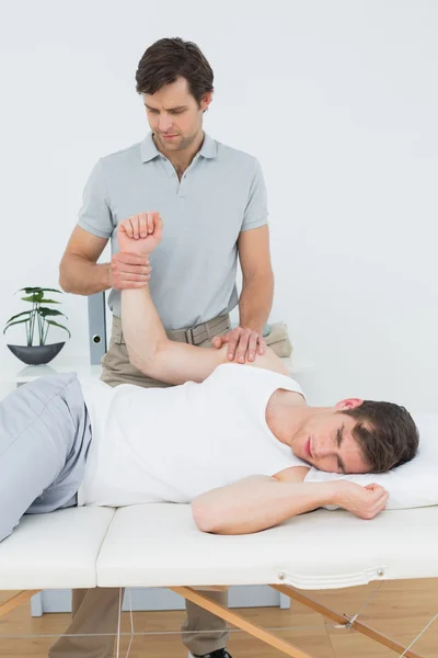 Fisioterapeuta masculino examinando una mano de un hombre joven — Foto de Stock