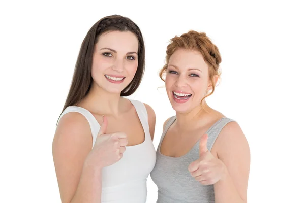 Två unga kvinnliga vänner gestikulerande tummen upp — Stockfoto