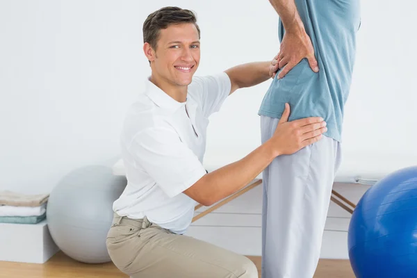 Mannelijke therapeut masseren mans lagere terug in gym ziekenhuis — Stockfoto