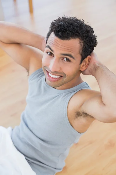 Uśmiechnięty mężczyzna robi brzuszki brzucha w salonie — Zdjęcie stockowe