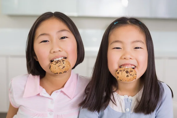 Portrait de deux jeunes filles souriantes dégustant des cookies — Photo