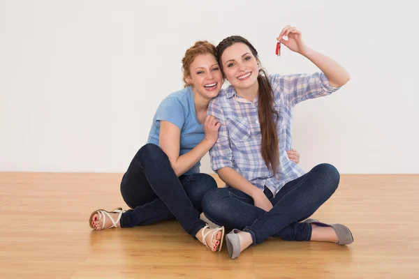 Female friends with house keys sitting on the floor — Stock Photo, Image