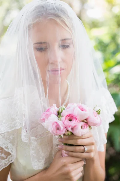 Calma novia usando velo sobre la cara sosteniendo ramo de rosas —  Fotos de Stock