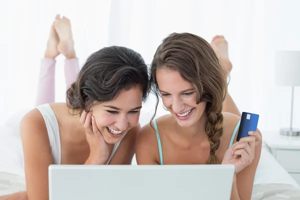 Happy avslappnad vänner gör online shopping i sängen — Stockfoto