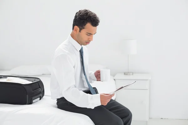 Businessman with cup reading newspaper at hotel room — Stock Photo, Image