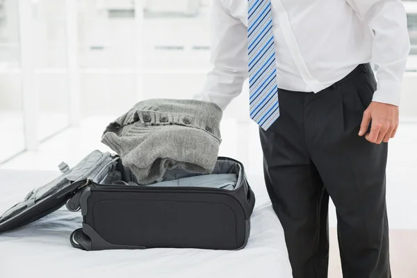 Mid section of a businessman unpacking luggage — Stock Photo, Image