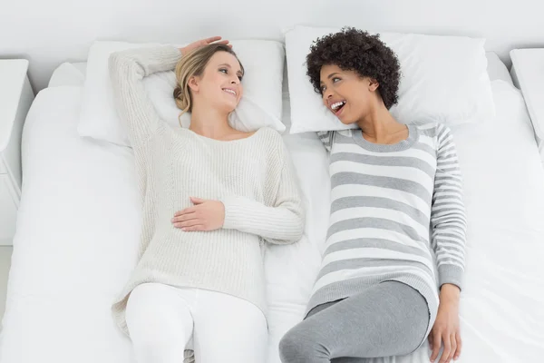 Two casual young female friends lying in bed — Stock Photo, Image