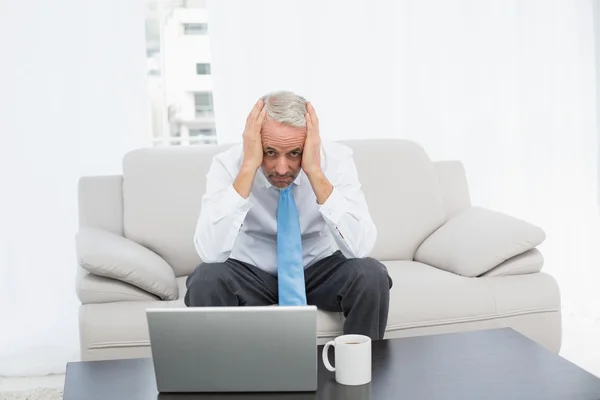 Portrait of a worried mature businessman with laptop at home — Stock Photo, Image