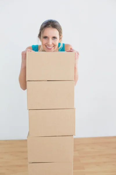新しい家でのボックスのスタックを持つ女性の笑みを浮かべてください。 — ストック写真