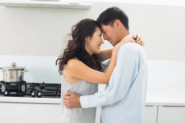 Vista lateral de un hombre abrazando mujer en la cocina —  Fotos de Stock