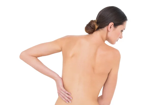 Rear view of a fit topless woman with back pain — Stock Photo, Image