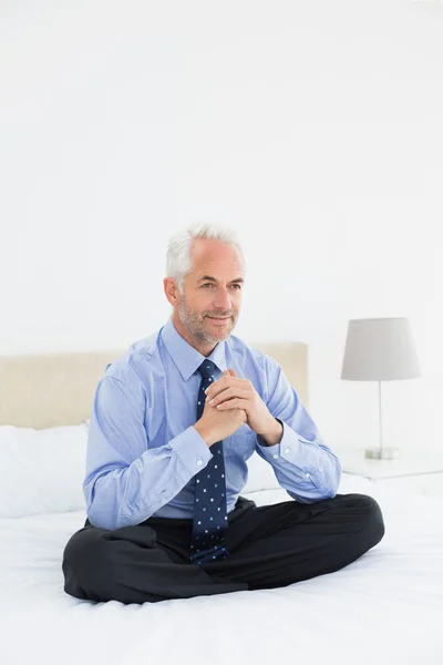 Ontspannen glimlachend volwassen zakenman zitten in bed — Stockfoto