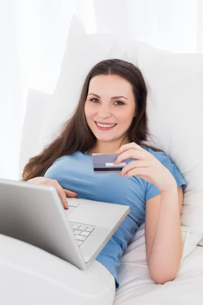 Casual jonge vrouw doen online winkelen in bed — Stockfoto