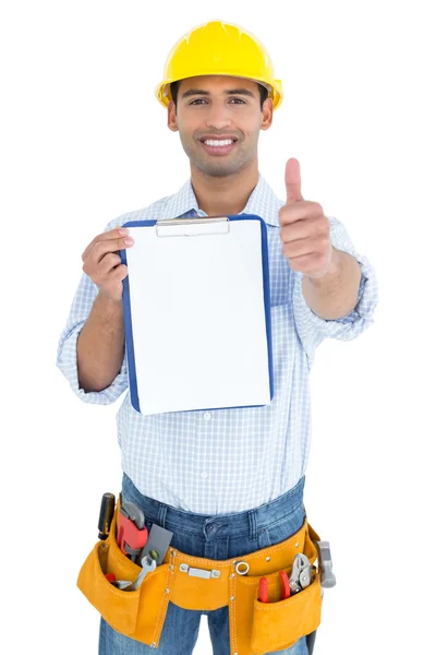 Handwerker mit gelbem Hut mit Klemmbrett, das Daumen hoch gestikuliert — Stockfoto