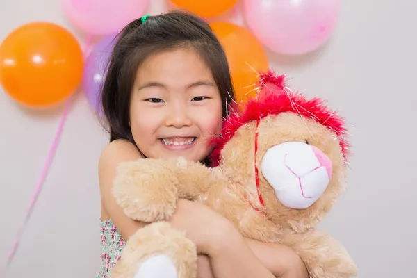 Menina bonito abraçando brinquedo macio em uma festa de aniversário — Fotografia de Stock
